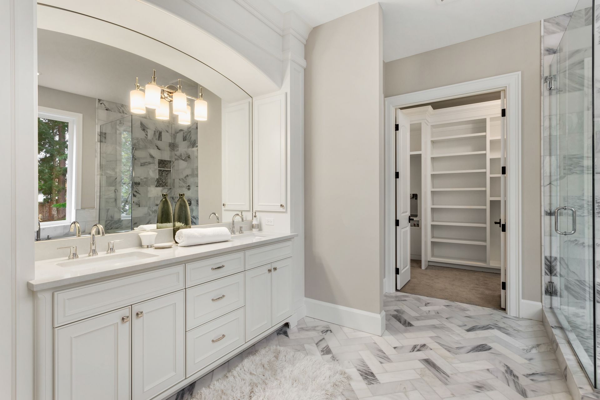 White bathroom with double vanity, marble floors, and walk-in closet.
