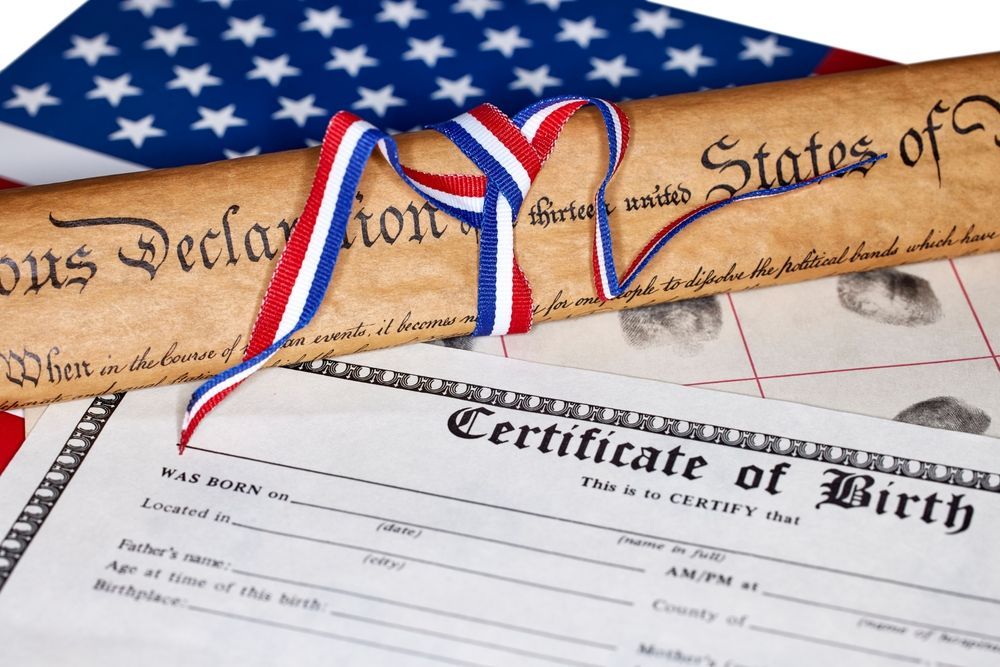 Declaration of Independence, birth certificate, and American flag tied with red, white, and blue ribbon.