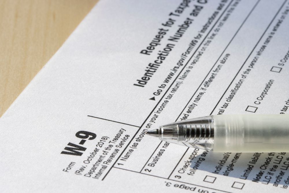 Close-up of a W-9 tax form with a pen resting on it.