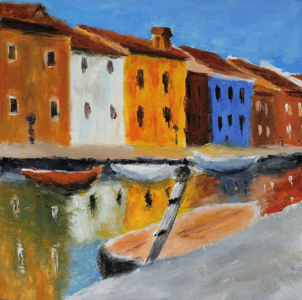 I colorati edifici sul lungomare si specchiano nelle acque calme accanto alle piccole imbarcazioni.