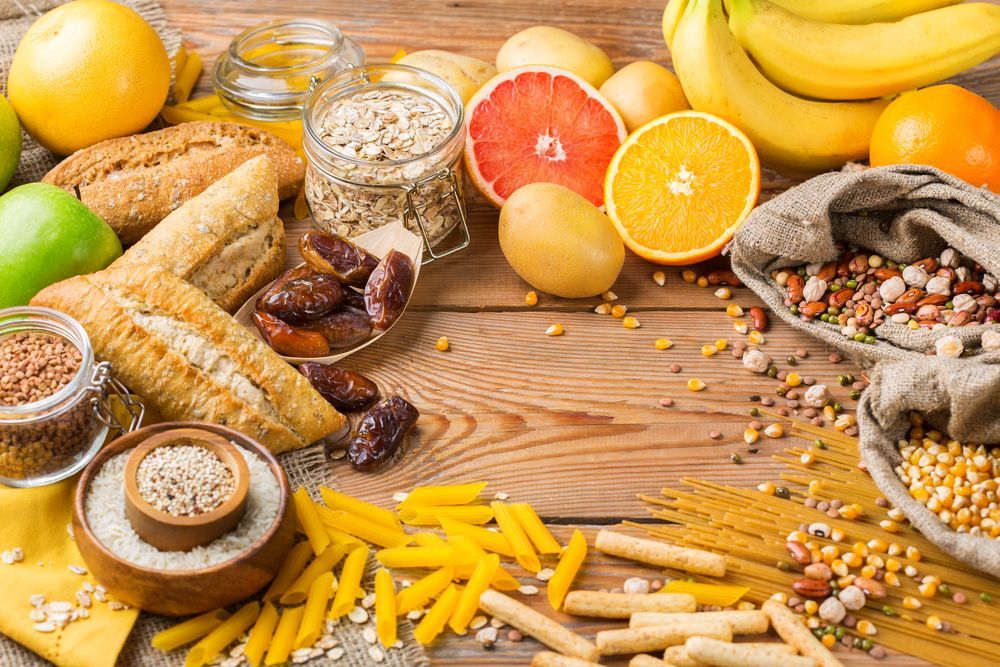 Un assortimento di pane, pasticcini, frutta e cereali disposti su un tavolo di legno, creando una colorata composizione gastronomica.