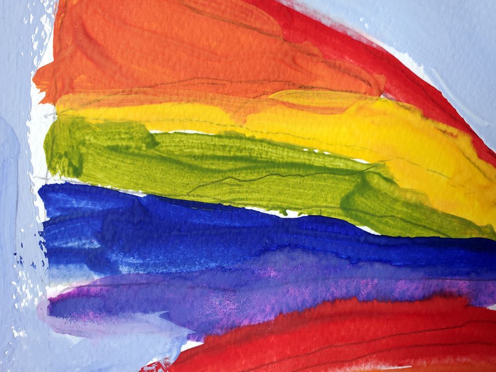 Bandiera arcobaleno dipinta con ampie pennellate su sfondo bianco.