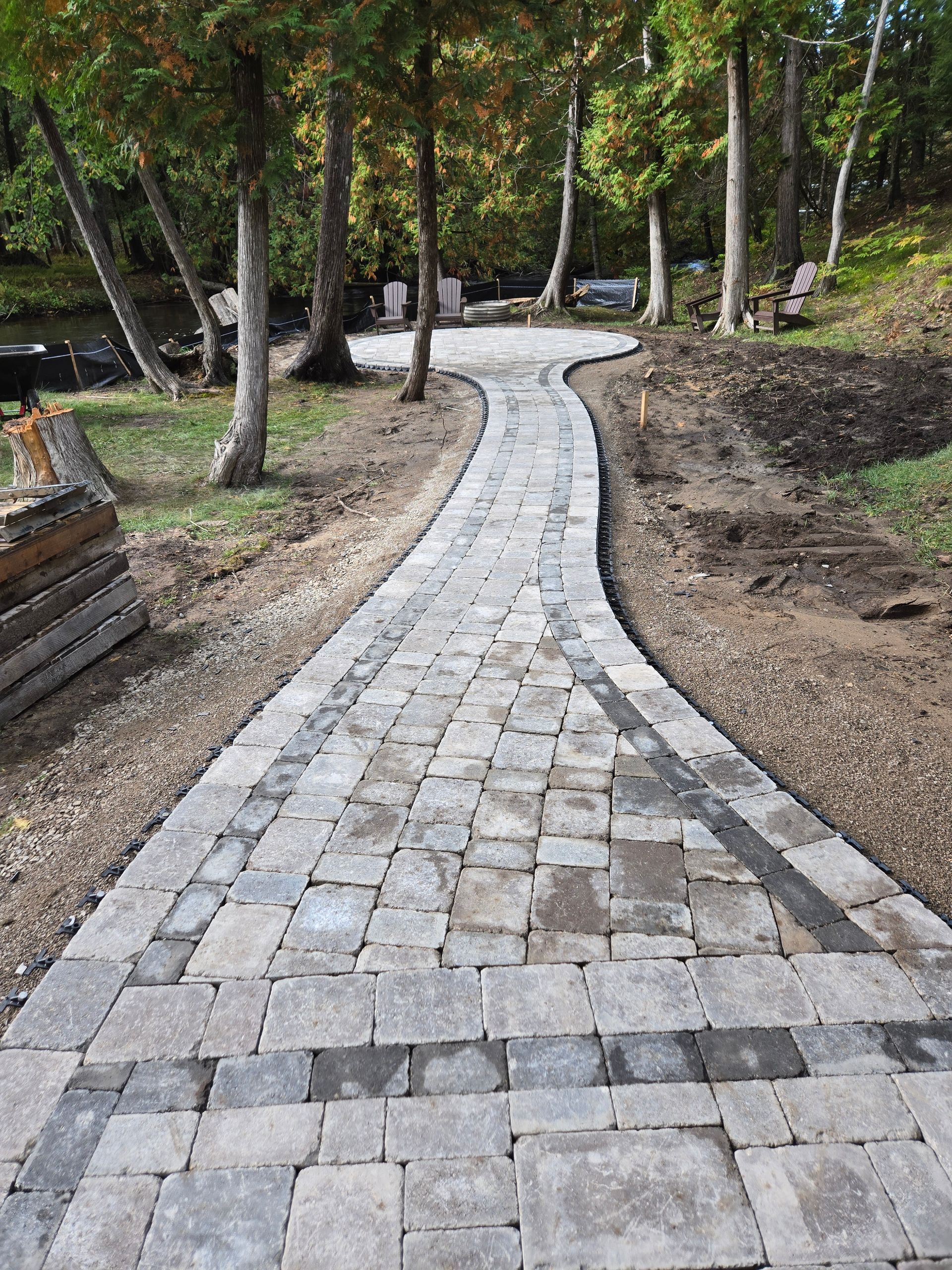 A winding garden path of stone slabs and gravel, illuminated by soft ground lights at dusk, surrounded by lush greenery. A winding garden path of stone slabs and gravel, illuminated by soft ground lights at dusk, surrounded by lush greenery.