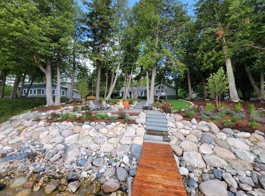 Three distinct textures—crushed grey stone, smooth river rocks, and green synthetic turf—divided by metal edging strips. Three distinct textures—crushed grey stone, smooth river rocks, and green synthetic turf—divided by metal edging strips.