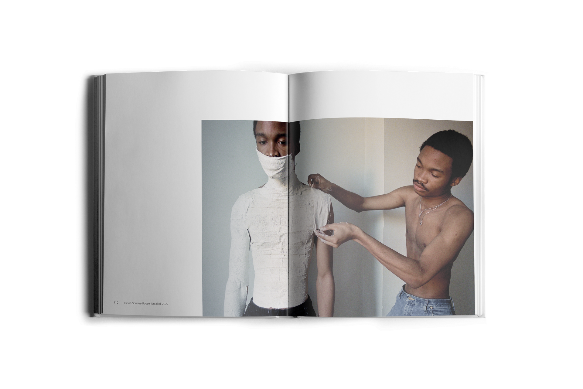 A person with a white cast on upper body and face. Another person adjusting the cast's shoulder. Interior setting.