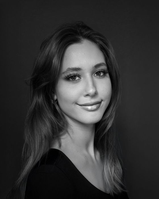 Woman with long hair smiles, posing for a portrait. Black and white photo.