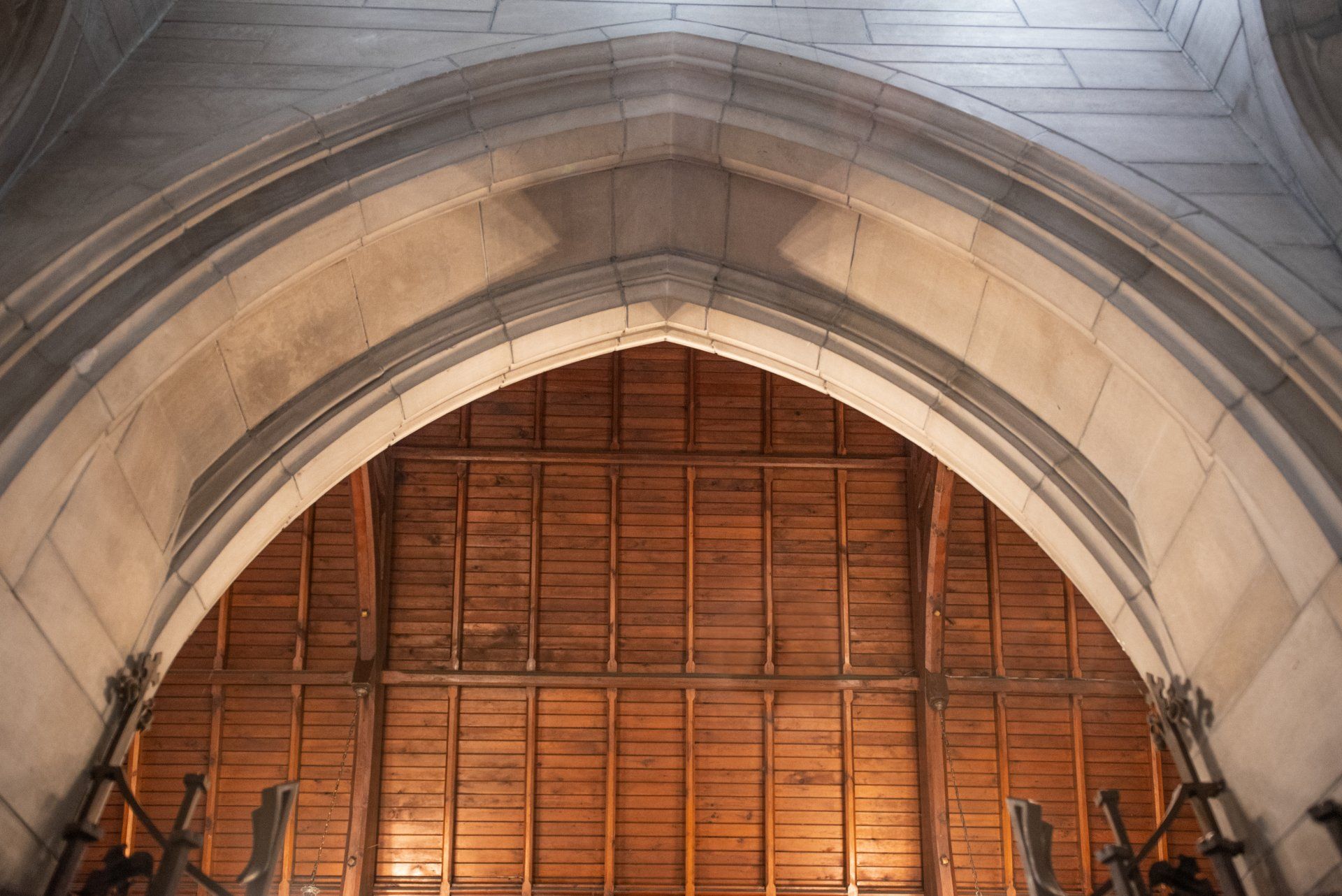 Gothic arched entryway, stone construction, framing a wooden interior with a raftered ceiling.