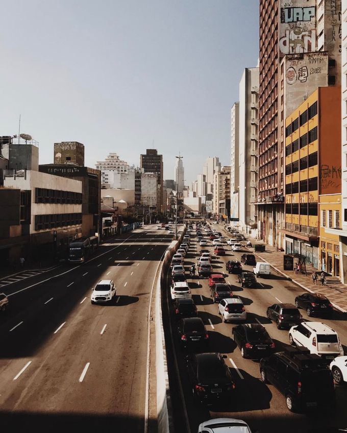 Busy urban highway lined with tall buildings and heavy traffic under a clear sky