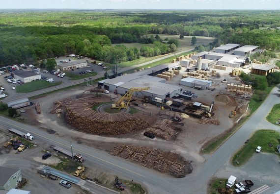 An aerial view of a large pile of logs surrounded by buildings and trees.