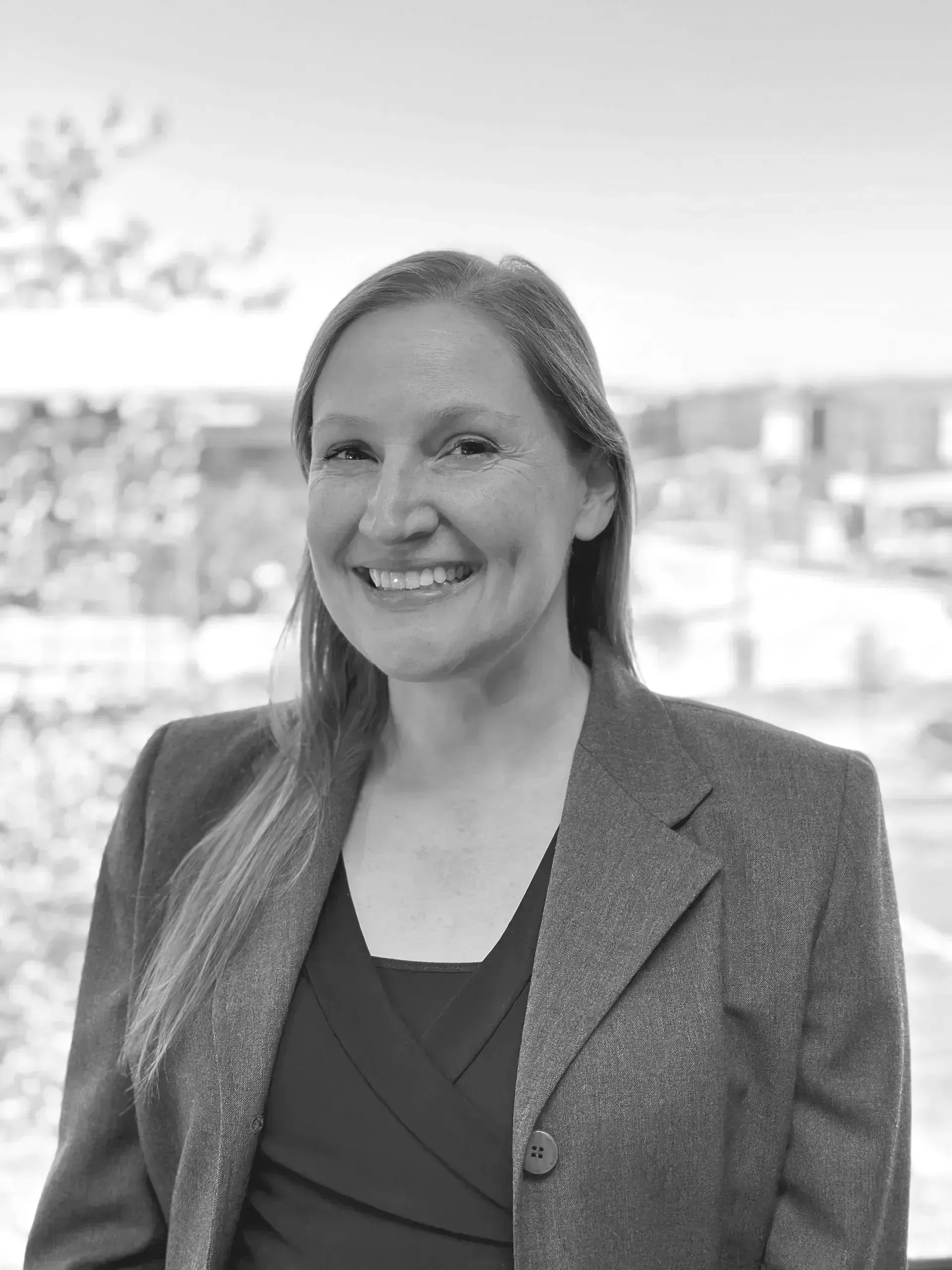 A woman in a suit is smiling in a black and white photo.