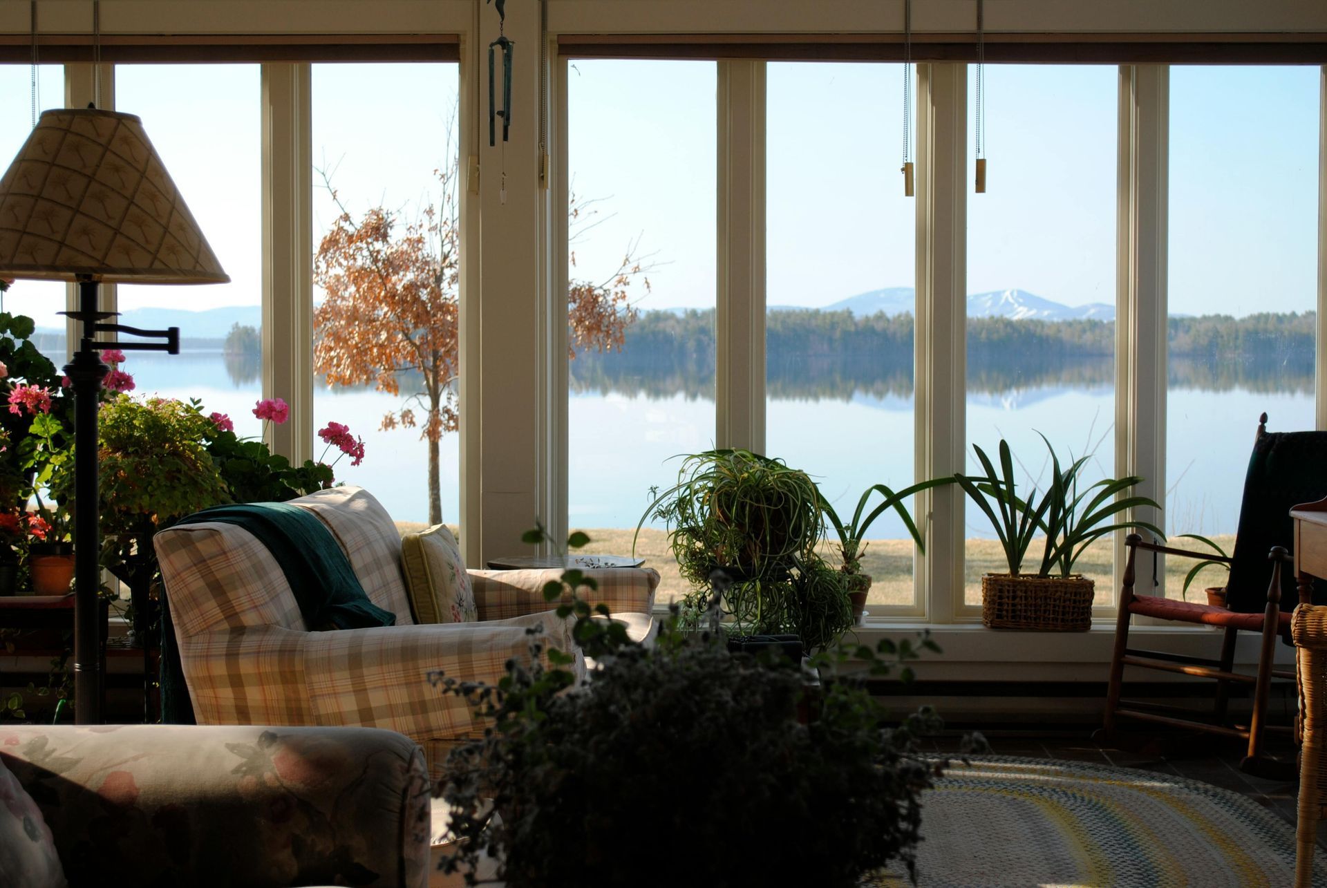 A modern home office with a wooden desk, shelves, and chairs against a blue wall, featuring a view of water and a city.