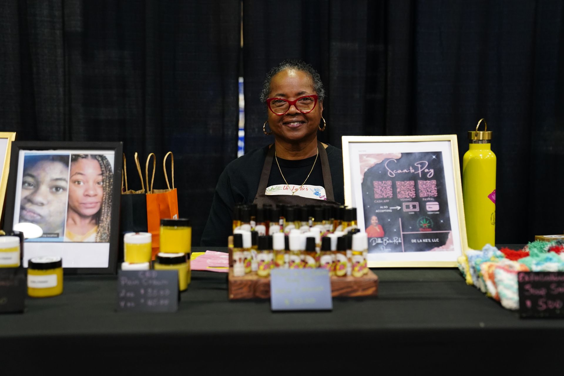 Woman seated behind memorial table with photos, candles, and flowers on a black tablecloth.
