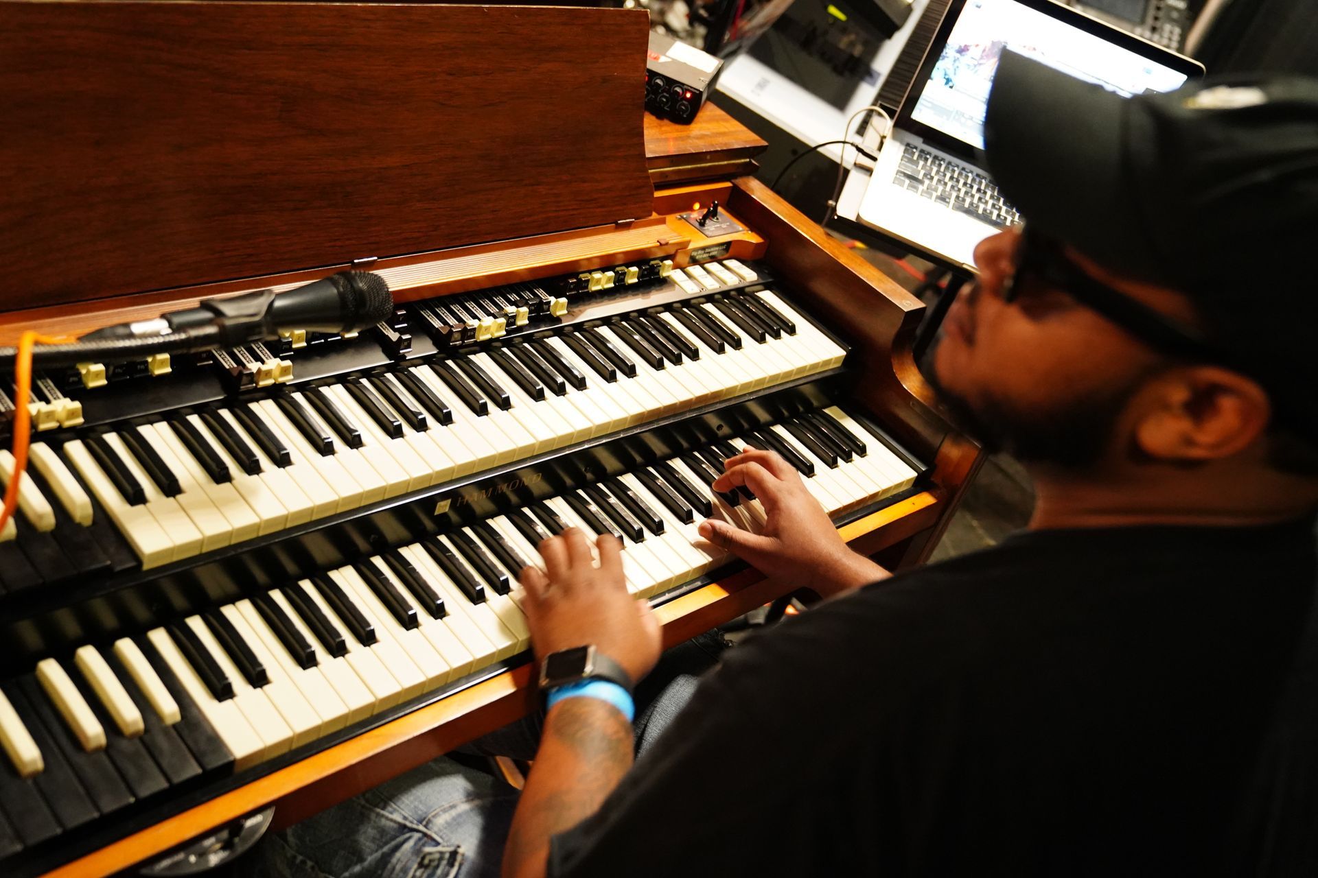 Man playing a two-tier keyboard organ in a wood-paneled studio