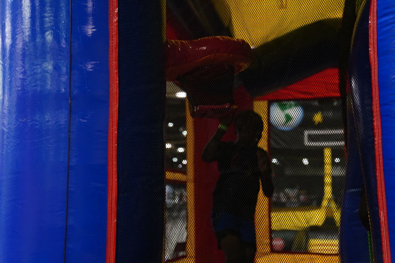 Person silhouetted inside a colorful indoor bounce house with blue, red, and yellow walls