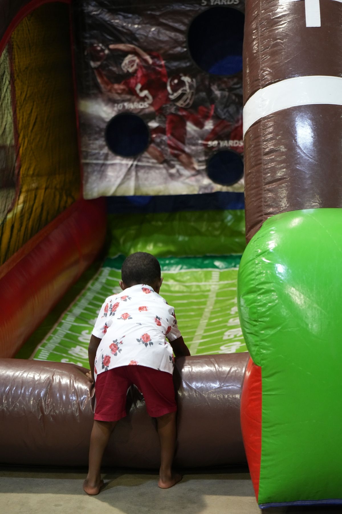 Child climbing into a colorful inflatable play structure with large holes and padded walls