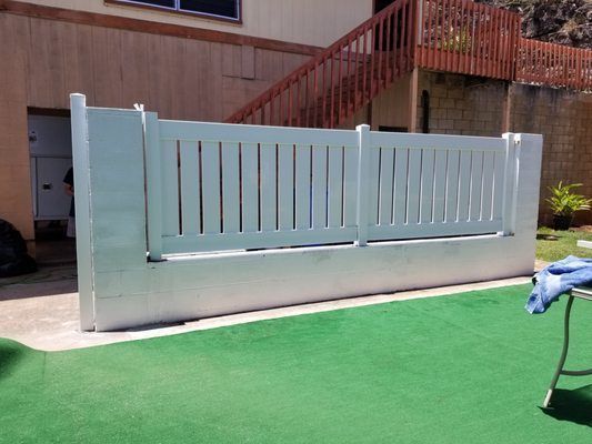 A white fence is in front of a house with stairs
