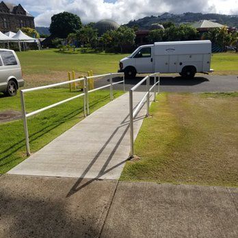 A white van is parked on the side of the road next to a ramp.