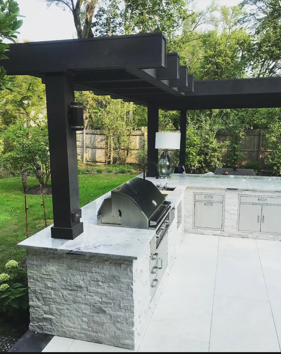 Outdoor kitchen with a grill, countertops, and a pergola.