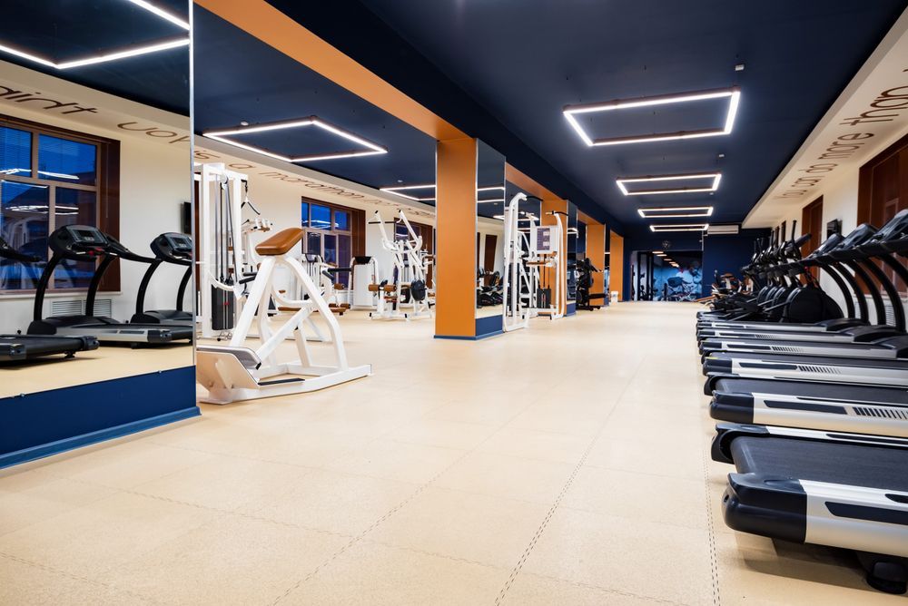 Un gimnasio bien iluminado con filas de cintas de correr y máquinas de ejercicio
