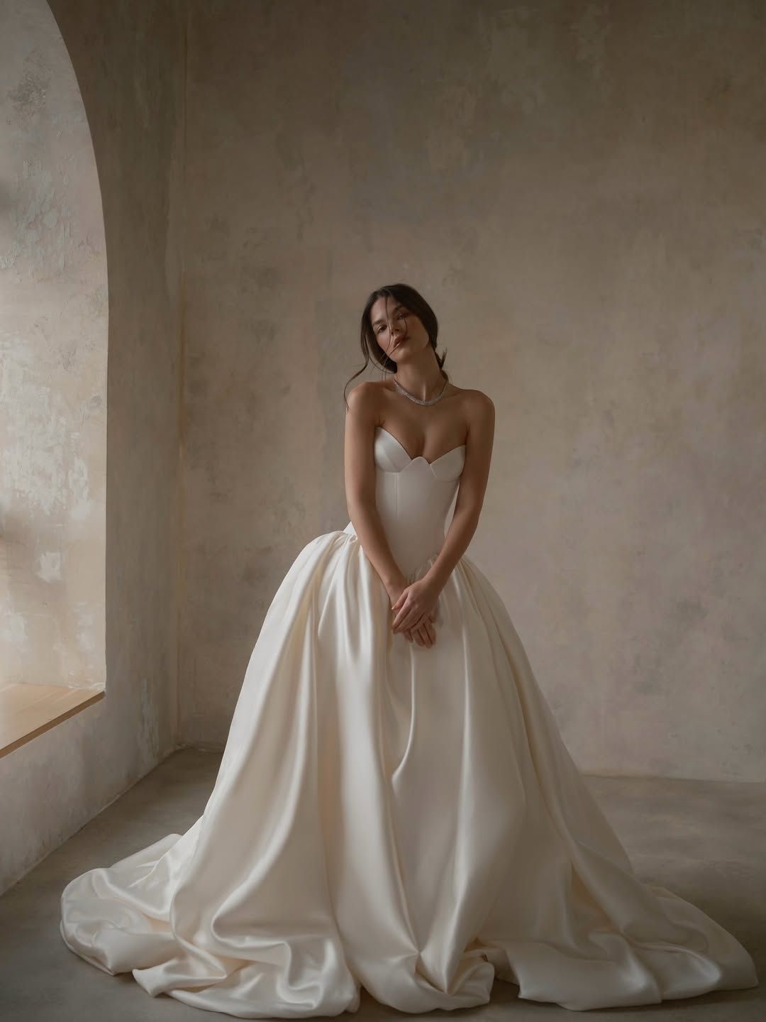 Bride in a white strapless gown posing in a minimalist room with soft natural light