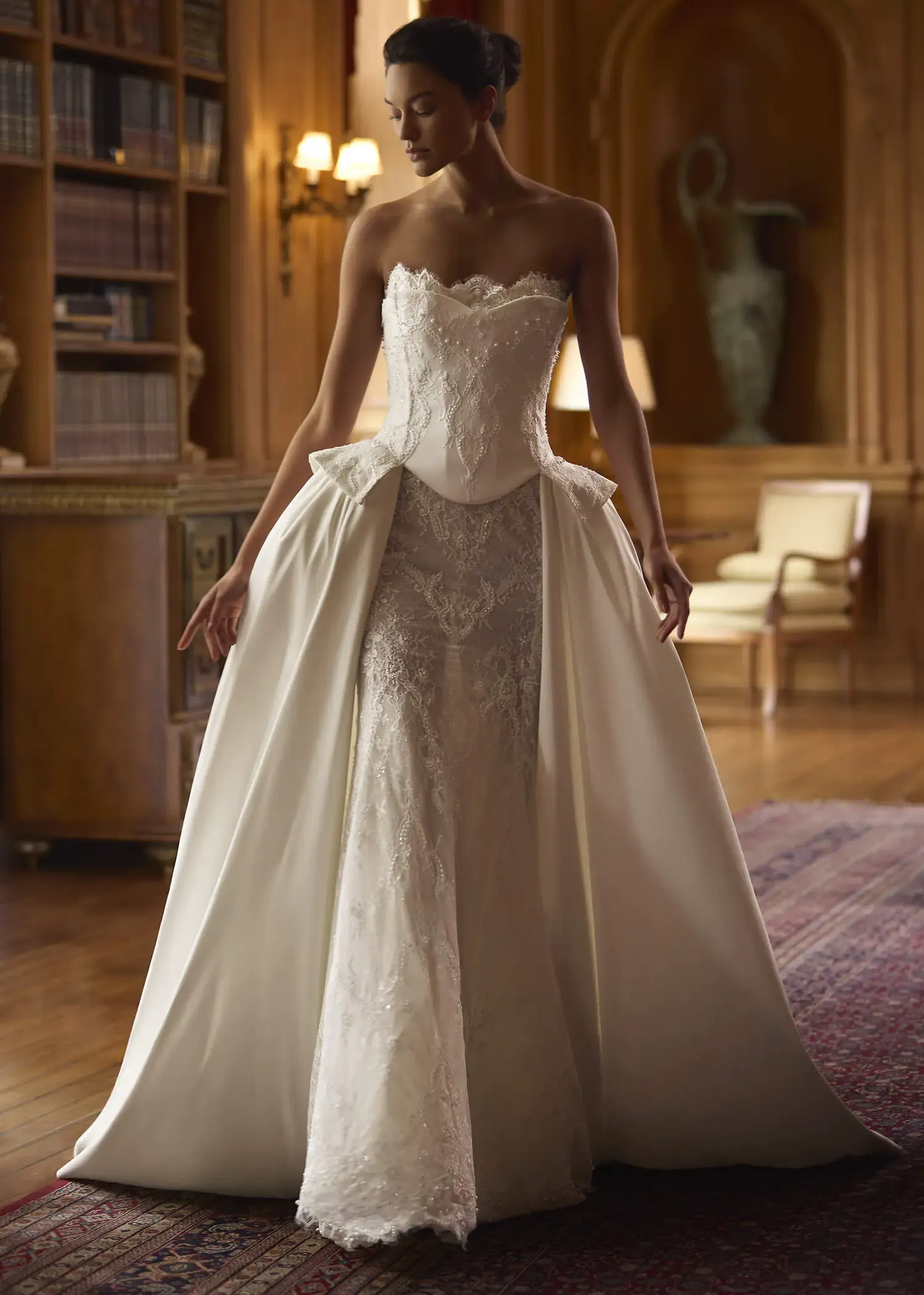 Woman in an elegant white ball gown standing in a grand wood-paneled room