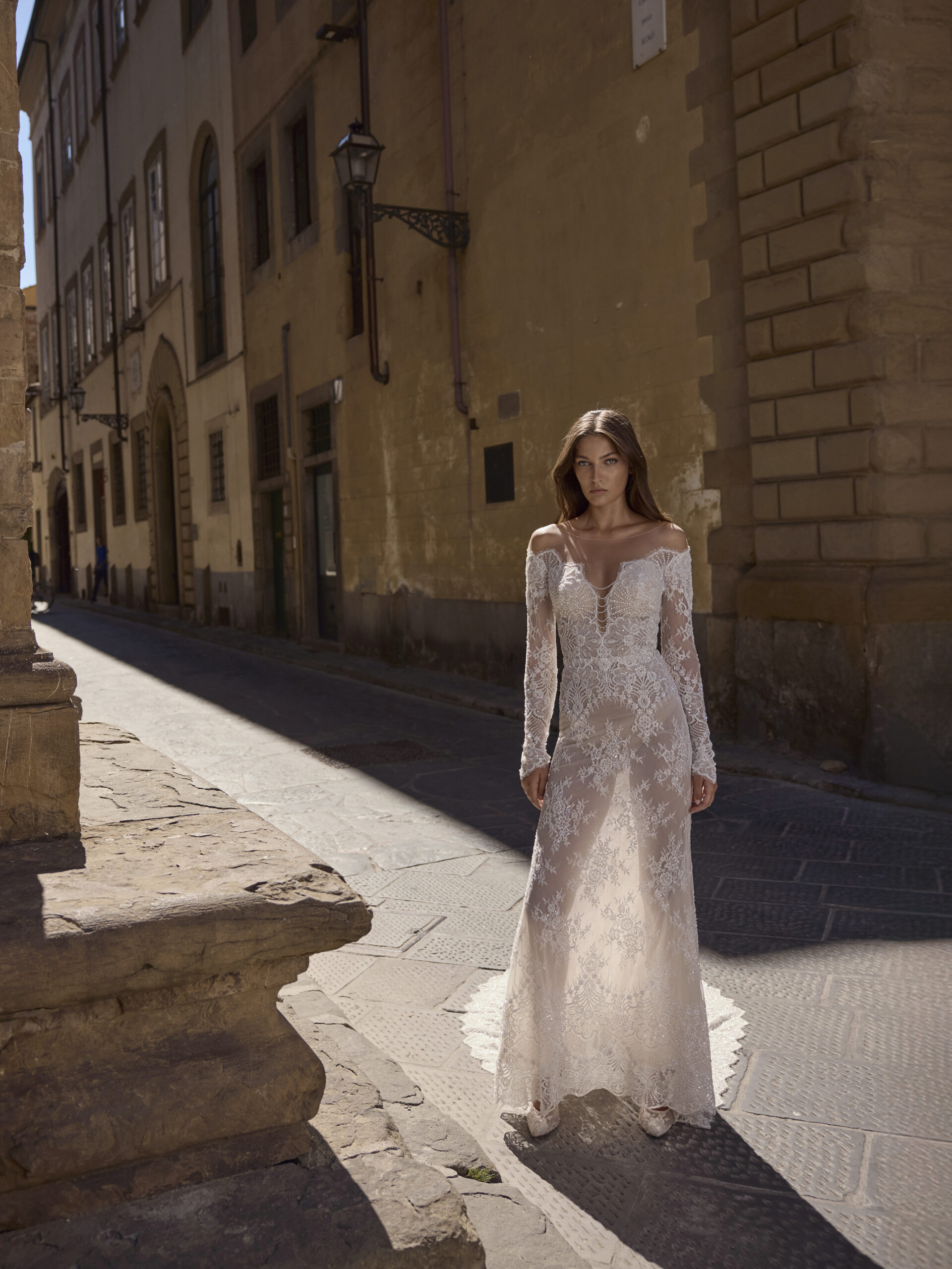 Michela Ferriero Wedding Gown, A woman in a wedding dress is standing on a sidewalk in front of a building.