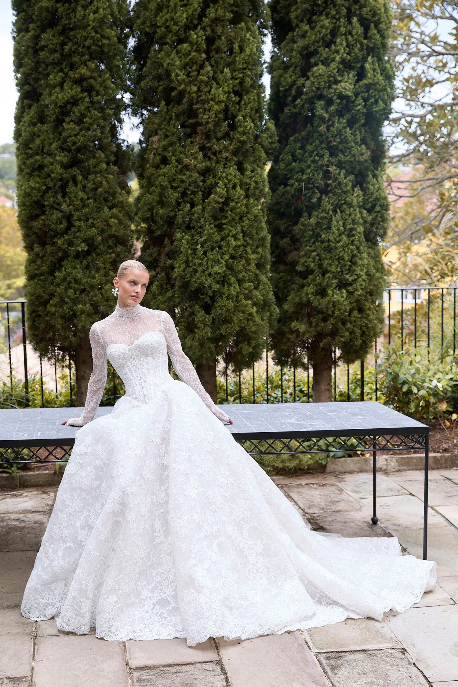 A woman in a wedding dress is standing in front of a window.