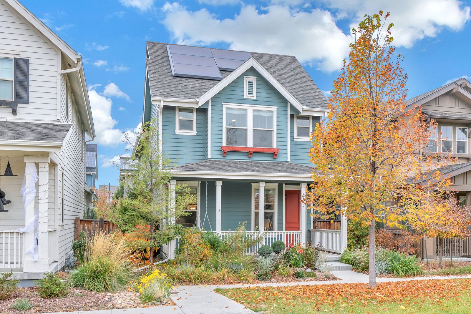A blue house with solar panels on the roof is for sale.