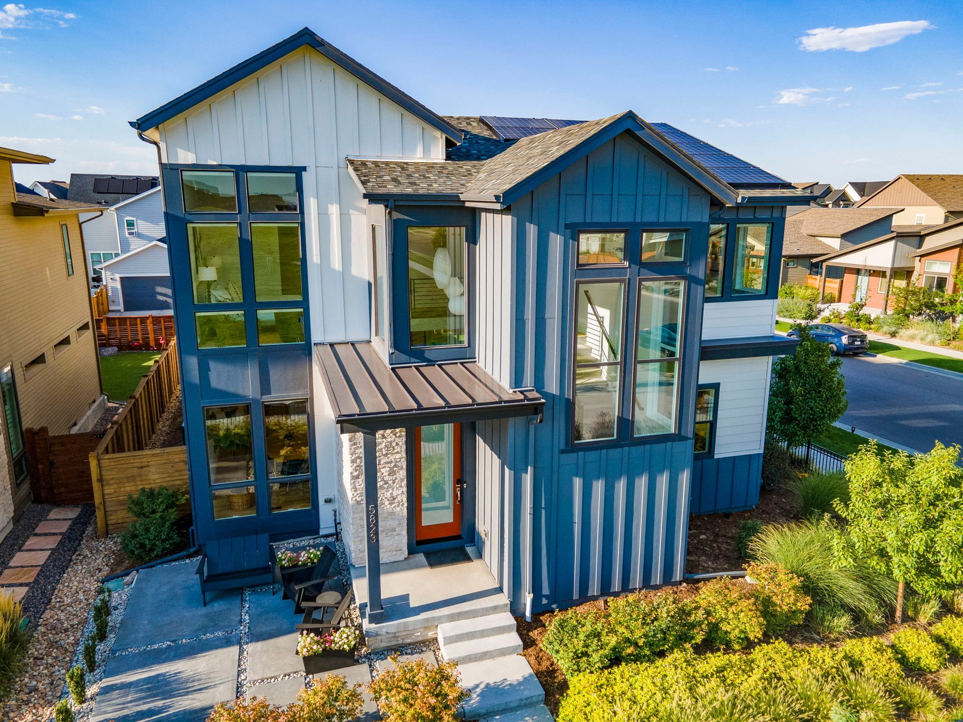 An aerial view of a blue and white house in a residential area.