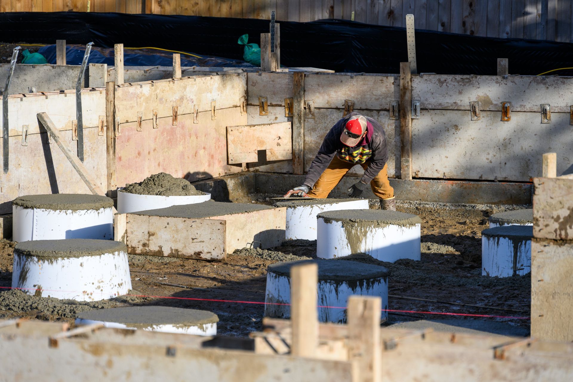A man wearing a hard hat is working on a construction site.