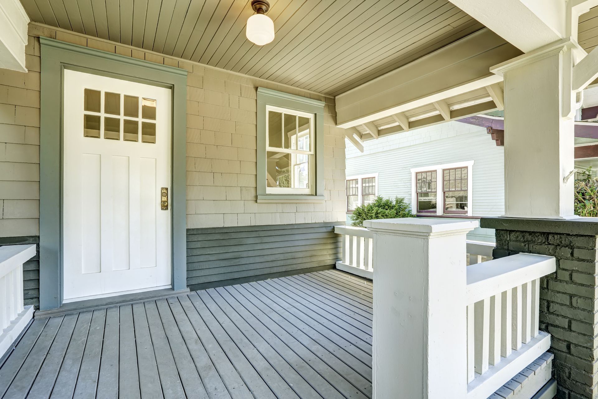 There is a porch with a white door and a white railing.