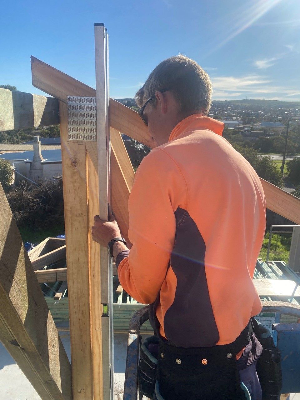 A man is measuring a piece of wood with a level.