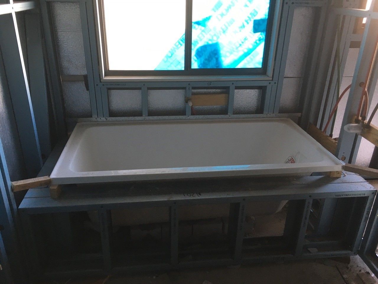 A bathtub is being built in a room with a window