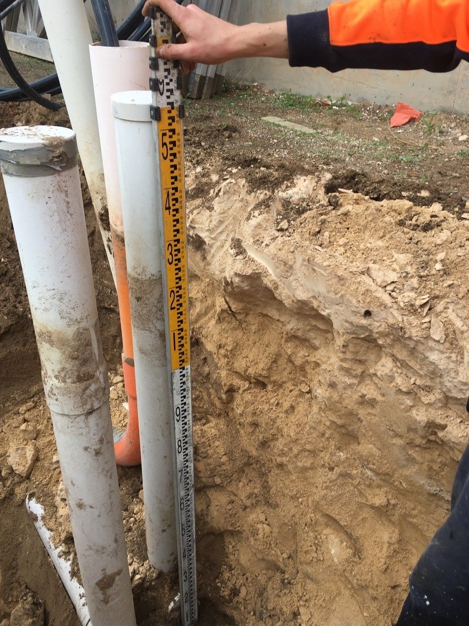 A man is measuring a pipe with a tape measure.