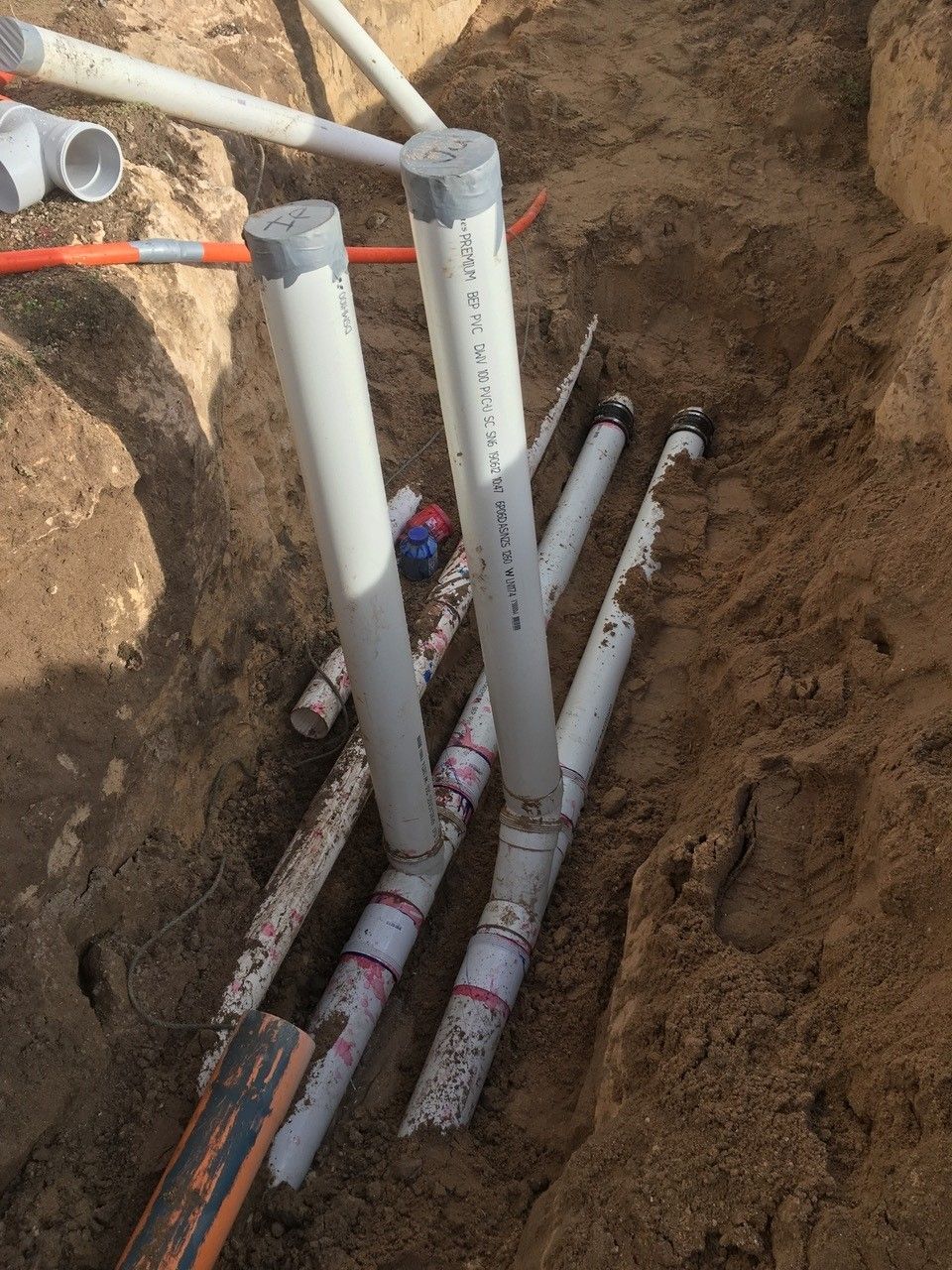 A bunch of pipes are laying in the dirt.