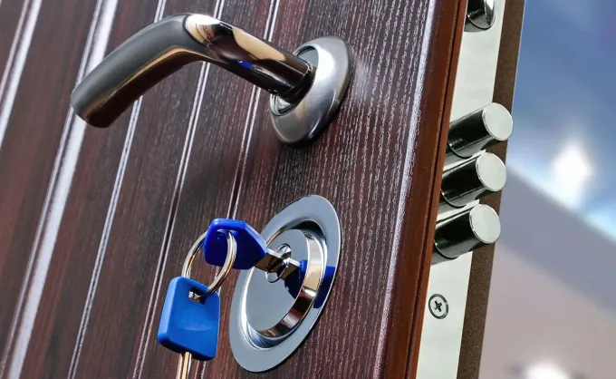 Primo piano di una macchina duplicatrice di chiavi in ​​metallo con struttura arancione e blu scuro, che mostra una chiave tenuta in una morsa metallica.