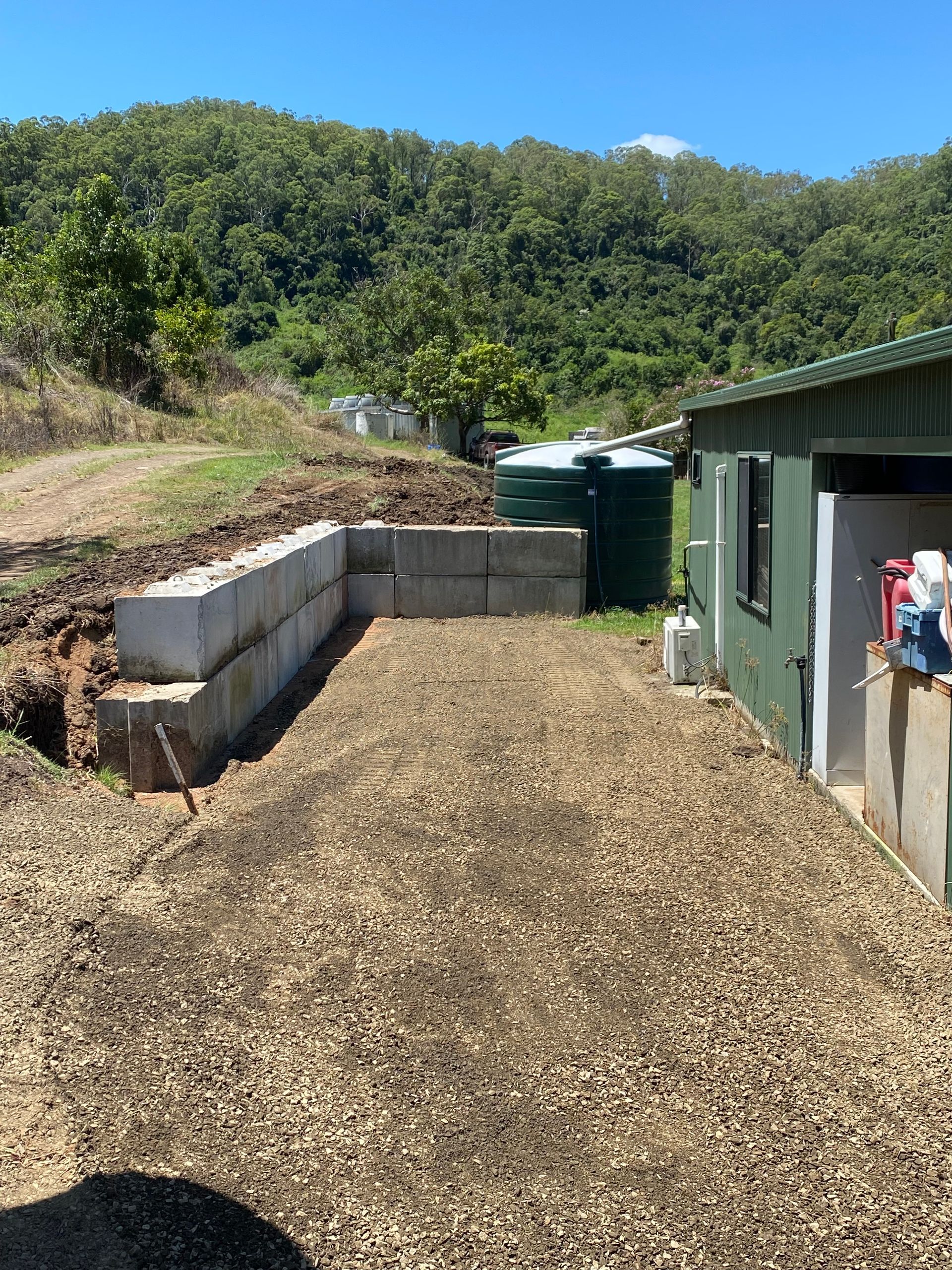 A Gravel Driveway With a Retaining Wall of Concrete Blocks — PVM Contracting in Woodburn, NSW