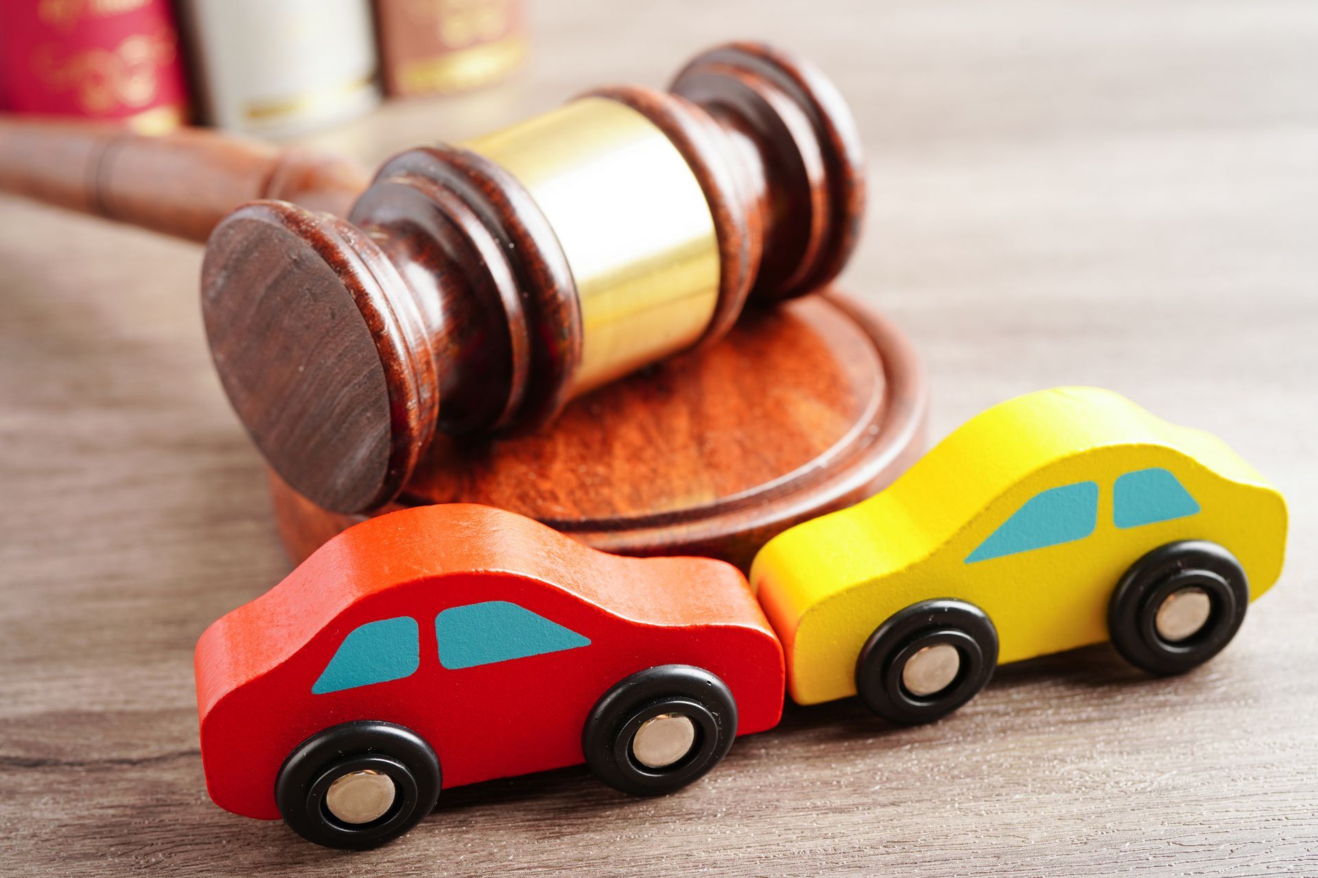 Two miniature cars simulating a crash and a wooden gavel on top of the car accident attorney’s table