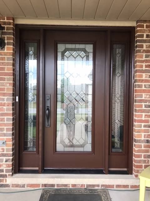 Front entry with a dark brown door, decorative glass panel, and sidelights set in a brick exterior.
