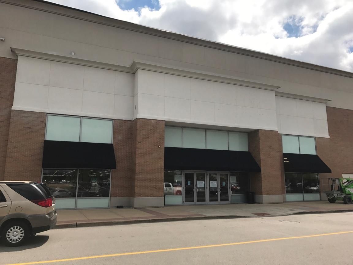 Storefront with black awnings and brick columns in a shopping plaza