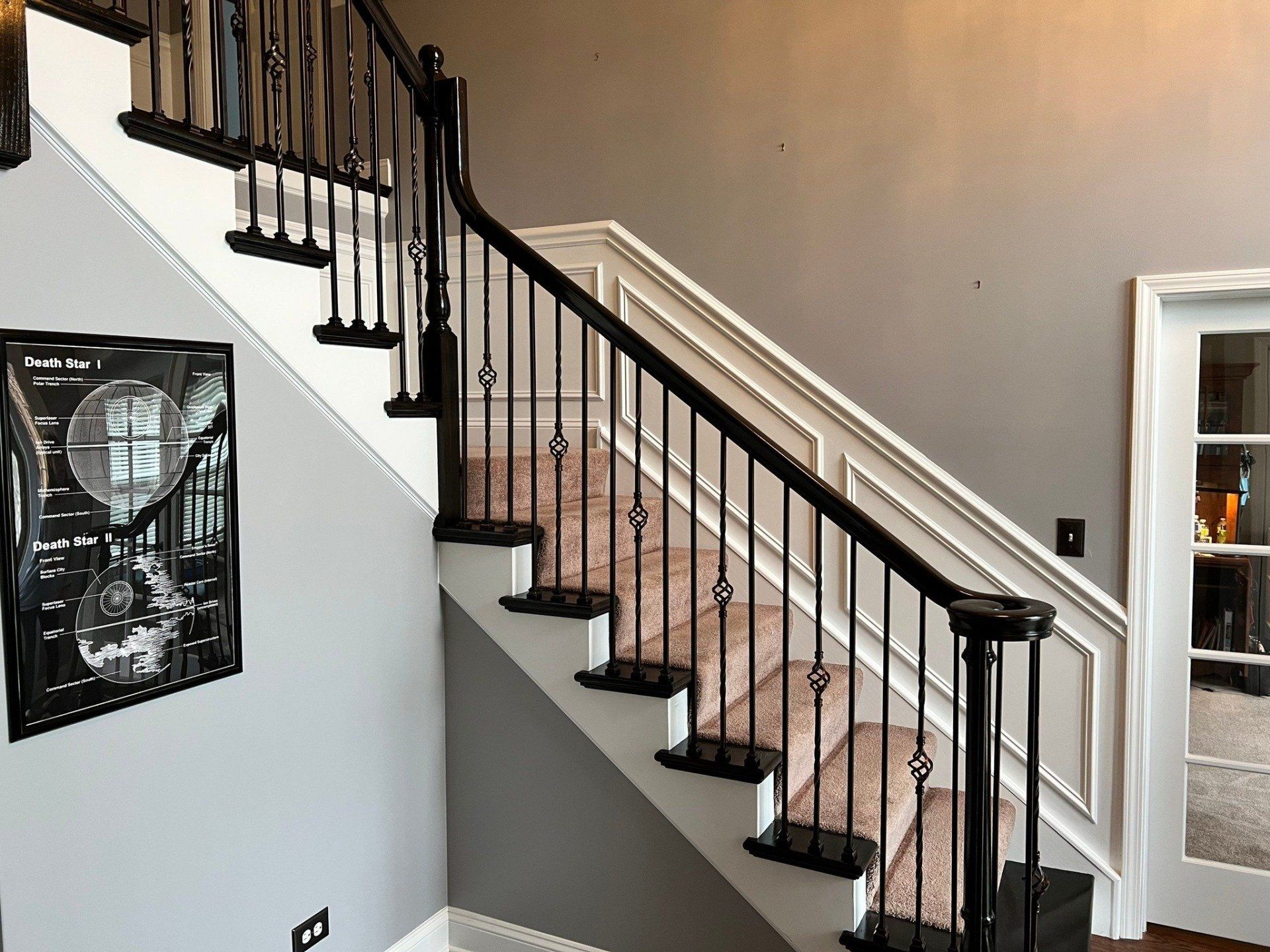 Staircase with black railing, white risers, and beige walls in a modern home interior