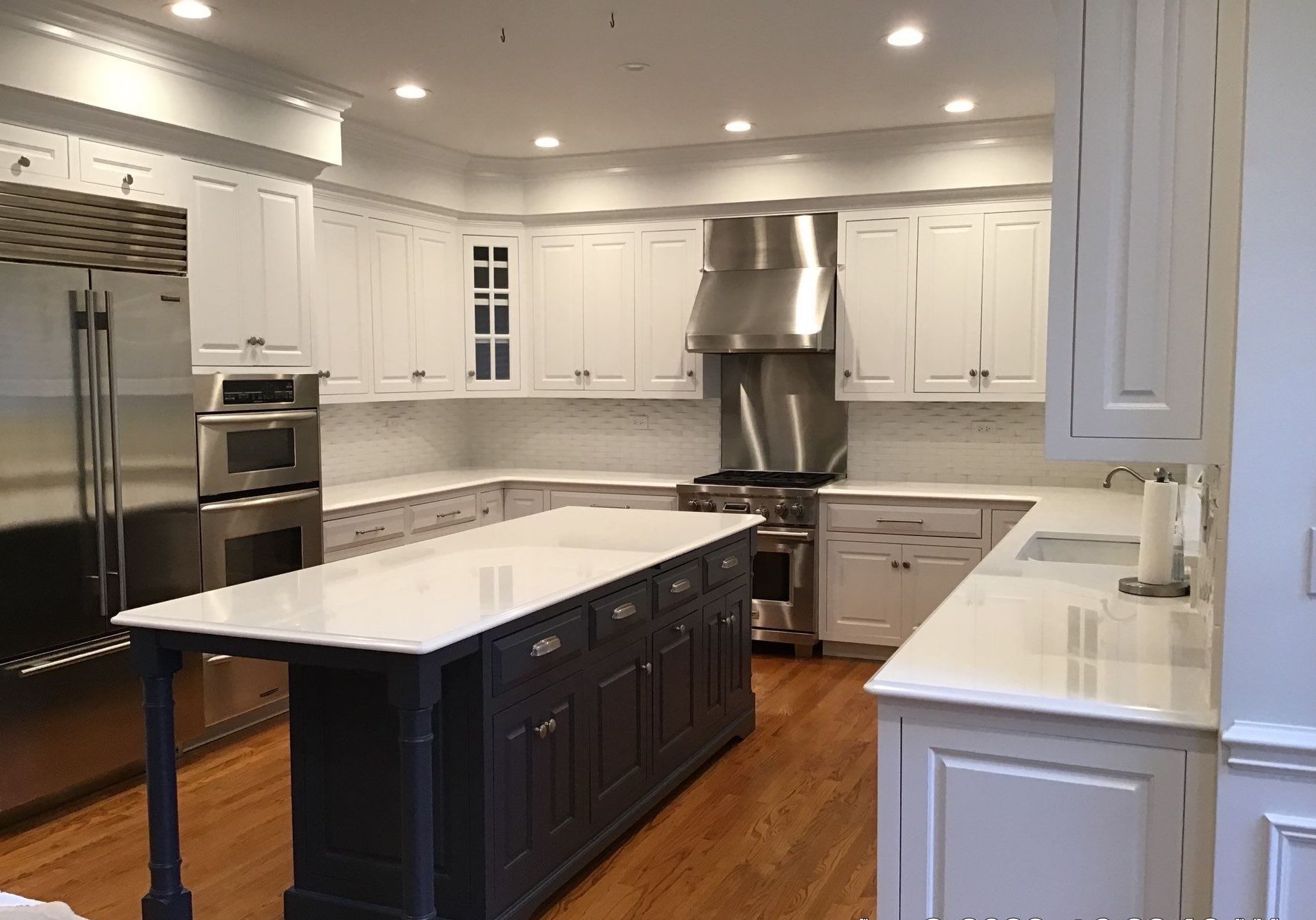 Bright modern kitchen with white cabinets, stainless steel appliances, and a dark island with a marble countertop