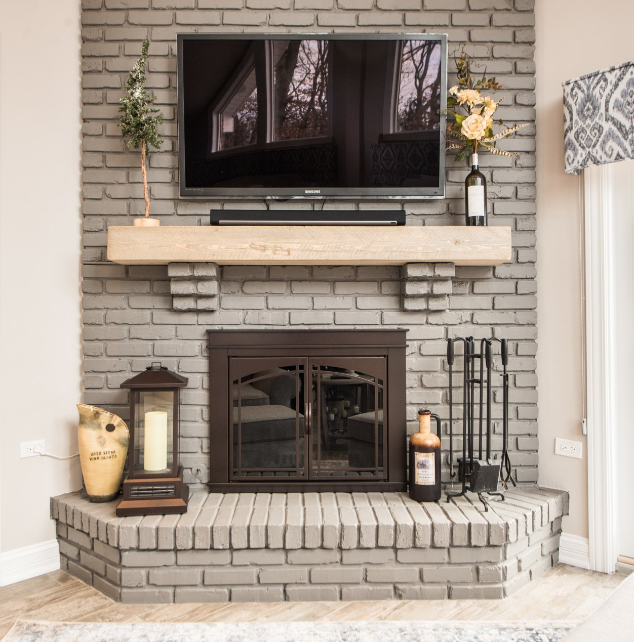 Brick fireplace with mounted TV, wooden mantel, and decorative lanterns in a living room