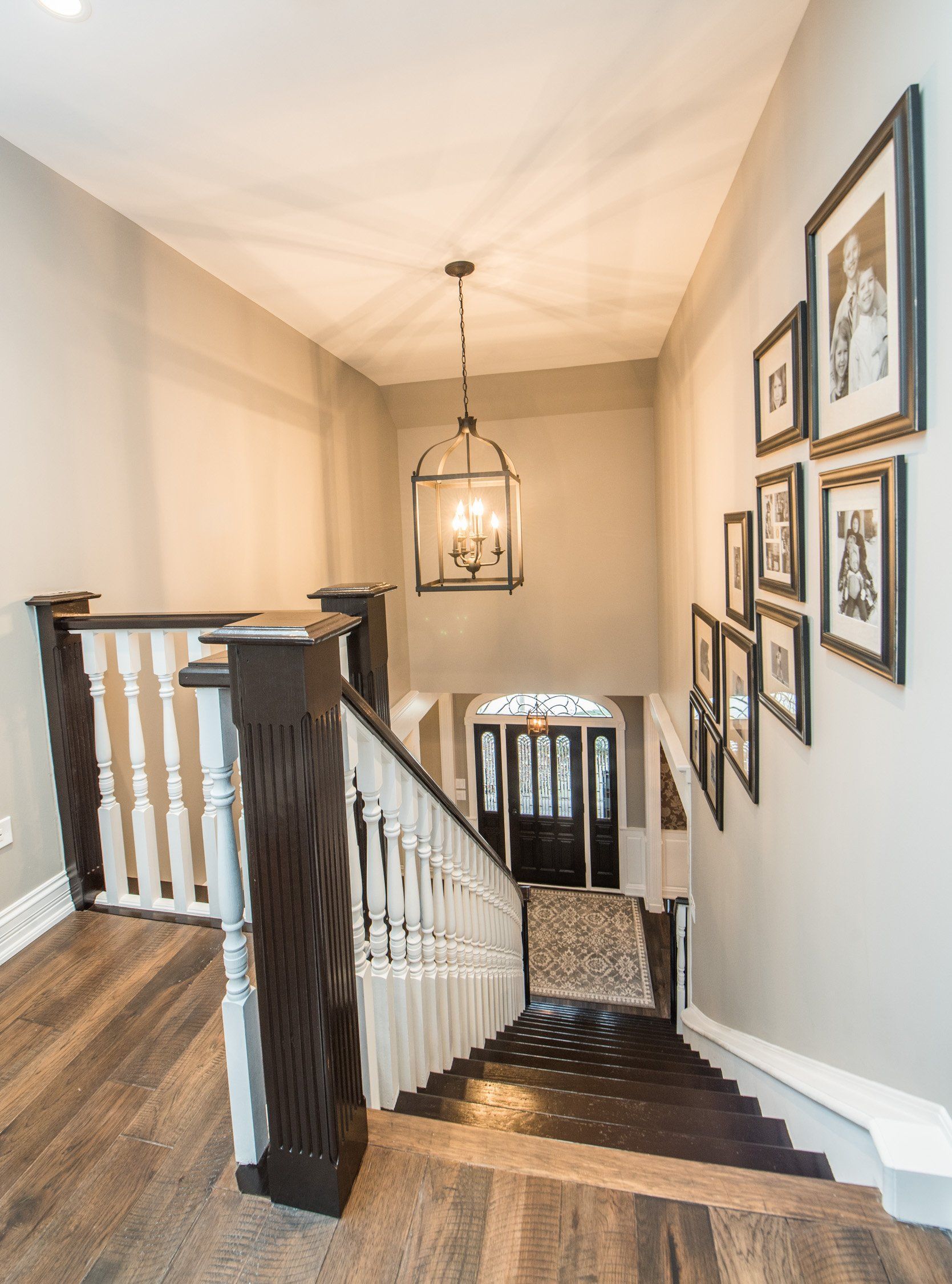 Staircase landing with dark wood railings, patterned runner, wall art, and hanging lantern light.