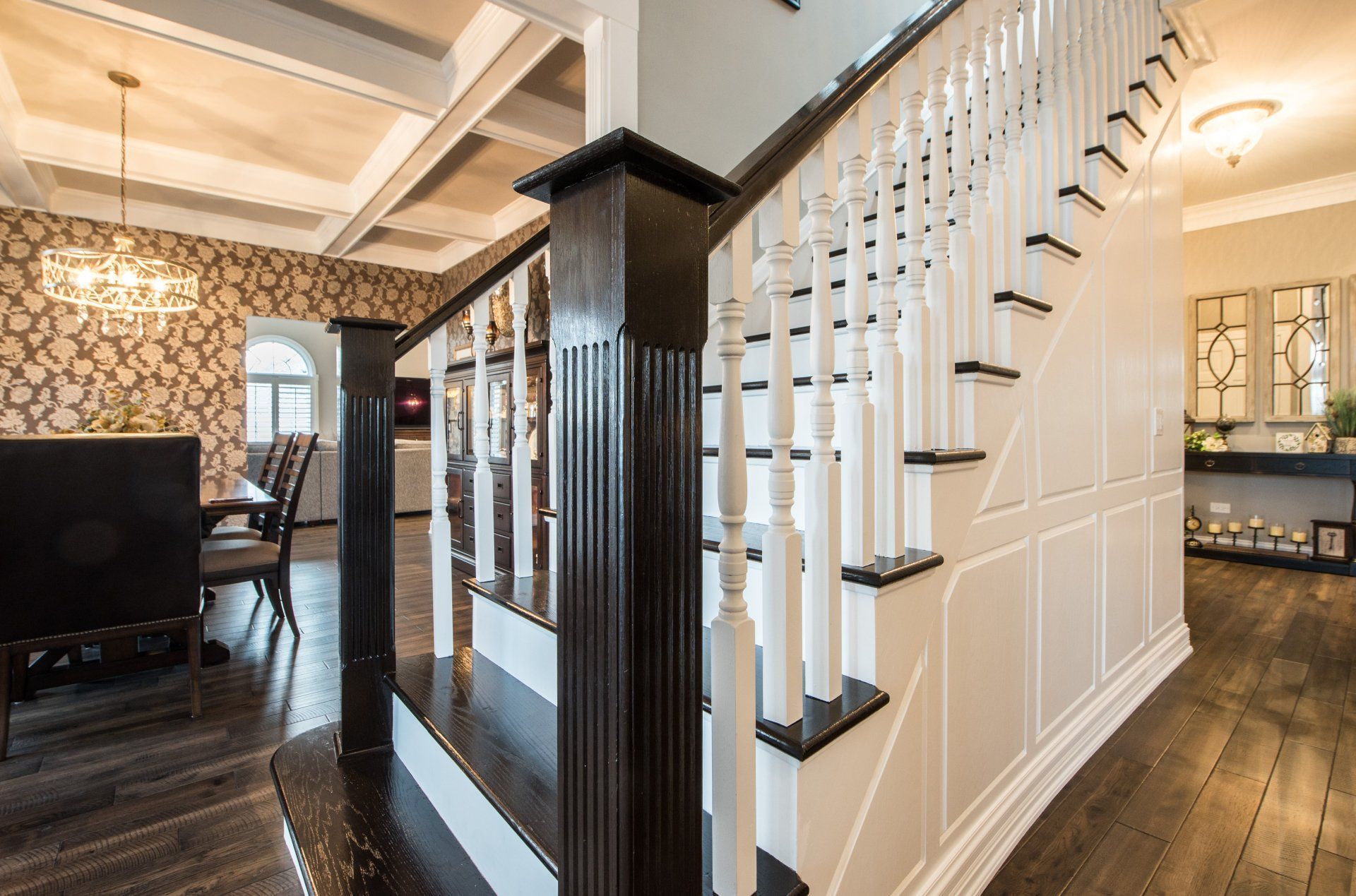 Elegant home interior with dark wood staircase, white paneling, and patterned wallpaper