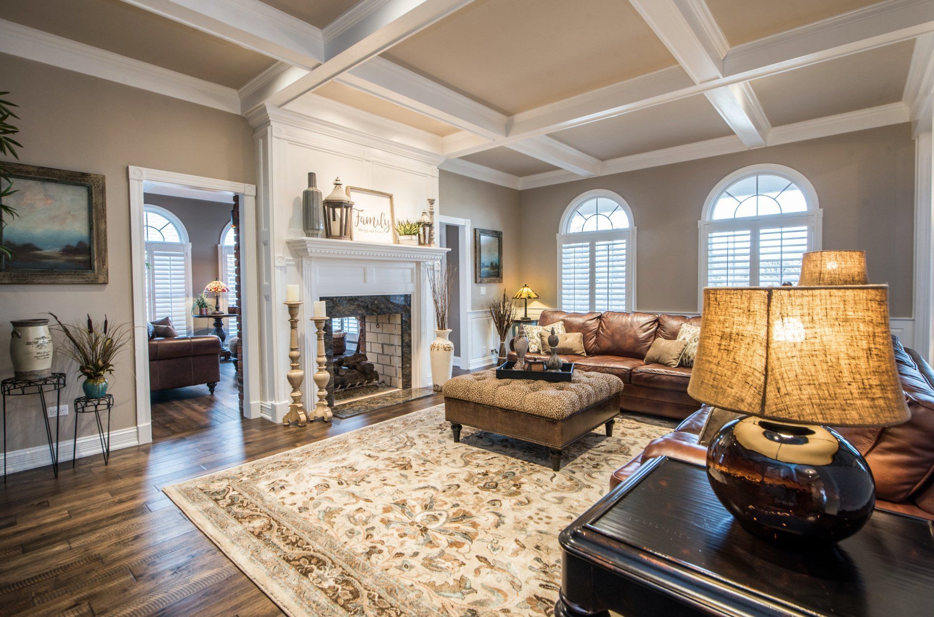 Elegant living room with fireplace, patterned rug, arched windows, and warm lamp lighting