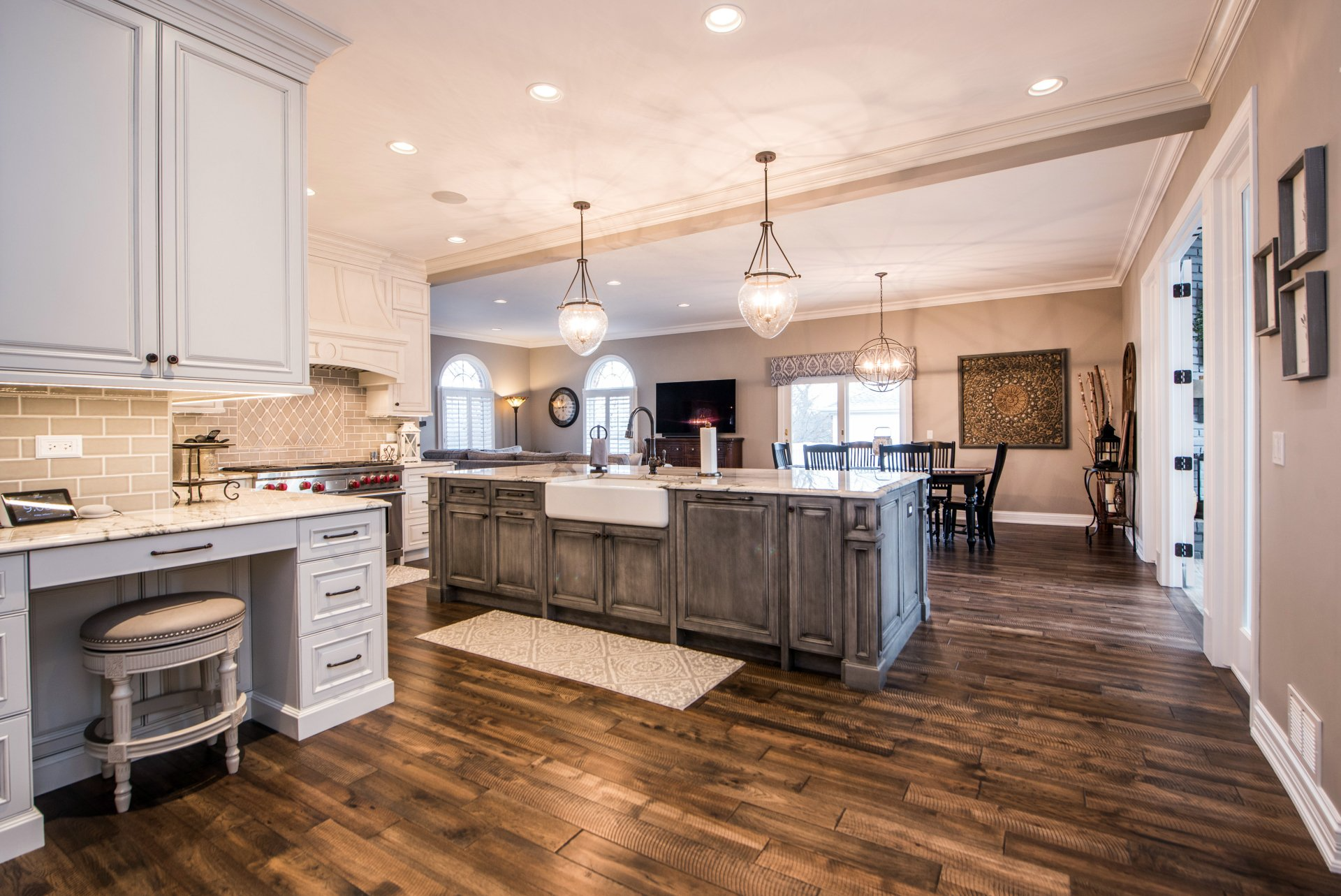 Bright kitchen with large island, white cabinets, and hardwood floors leading to a dining area