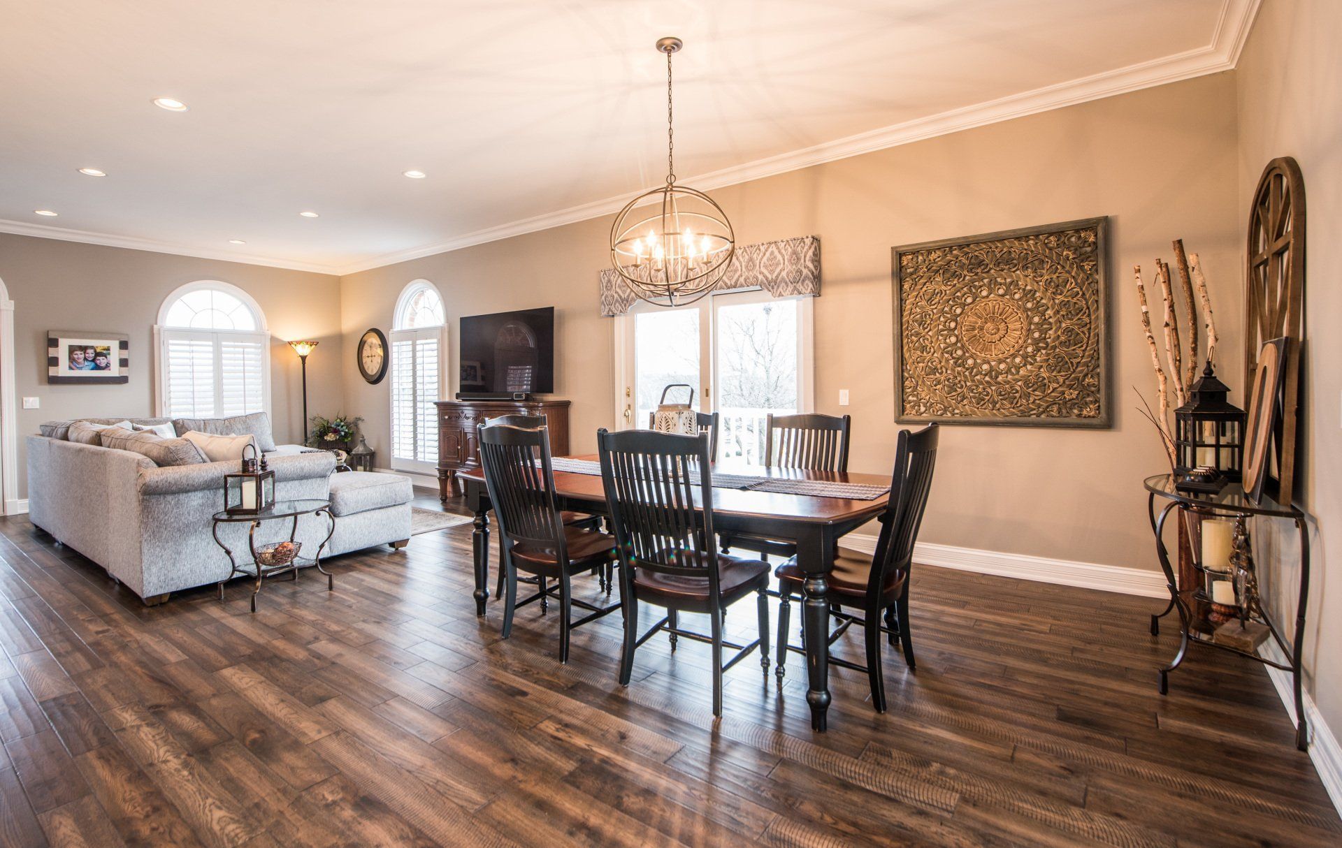Bright open living-dining room with dark wood floors, white sofa, and a chandelier over the dining table