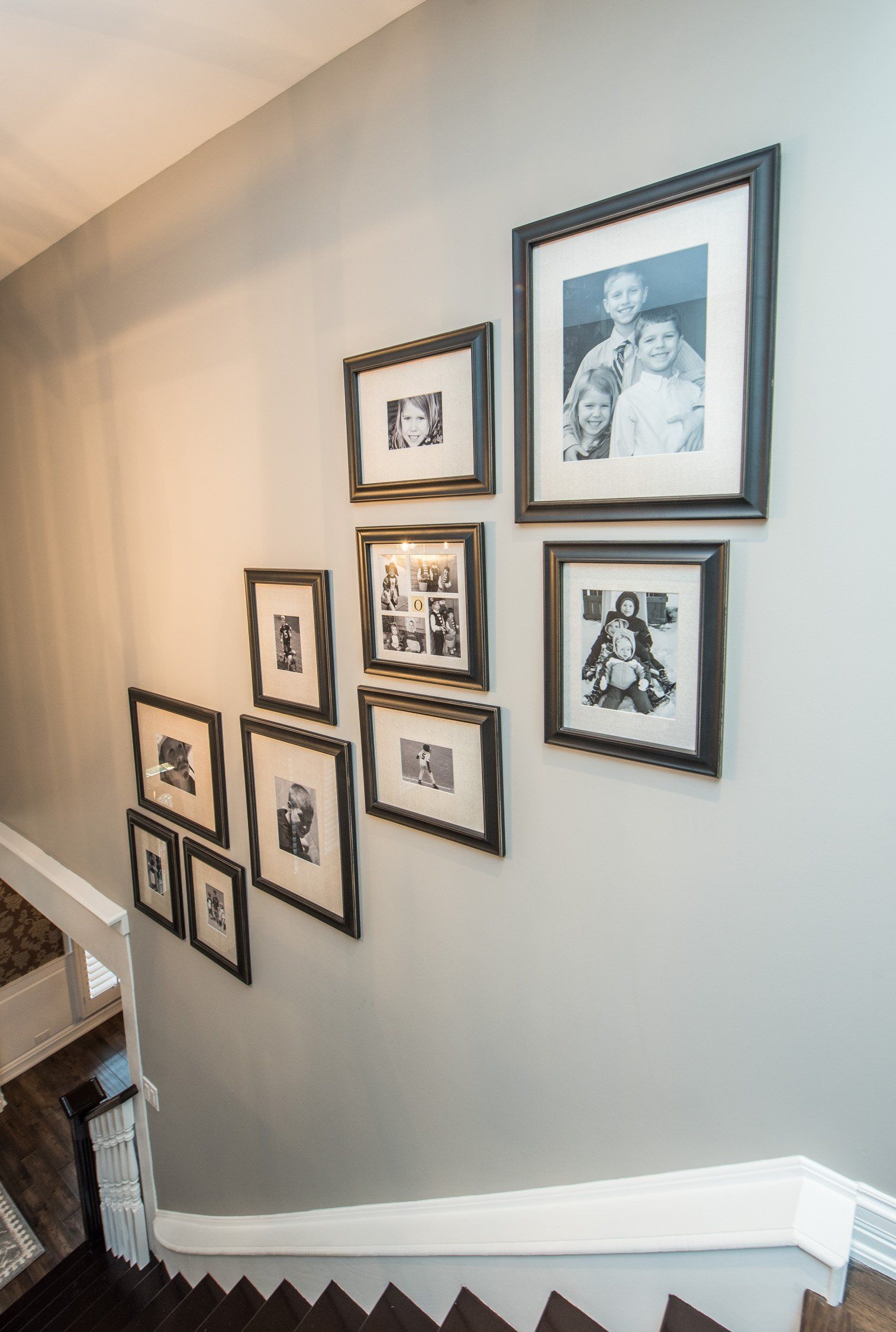 Framed black-and-white photos arranged diagonally on a light stairway wall.