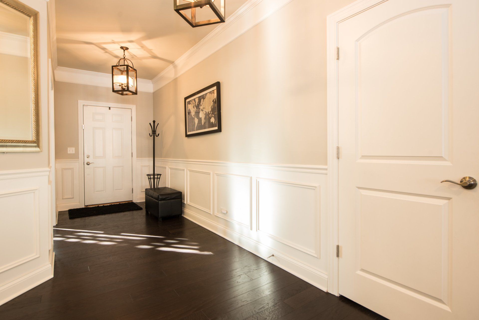Bright hallway with white doors, beige walls, dark floor, and hanging lantern lights.